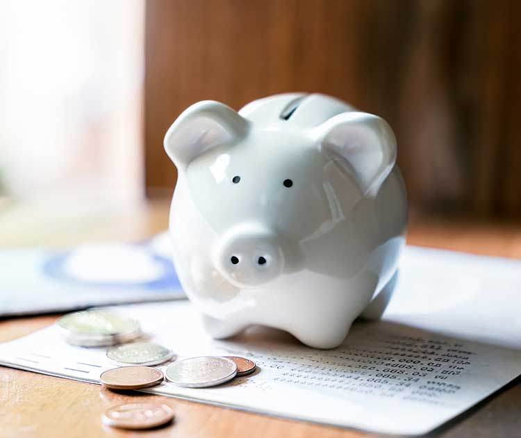 Piggy bank with coins on top of financial paperwork.