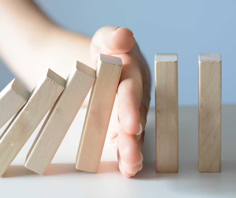 Faling trail of domino-like blocks stopped by a hand.