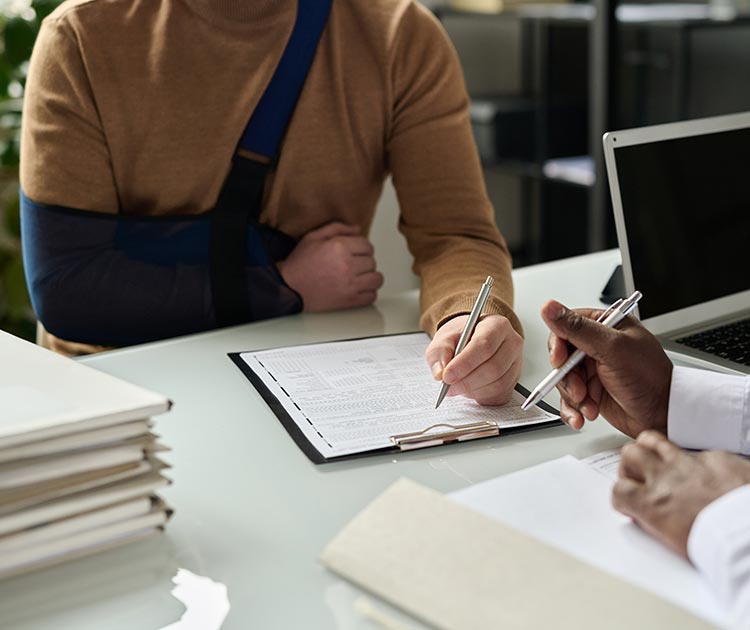 Person with casted arm completing forms with person behind desk.