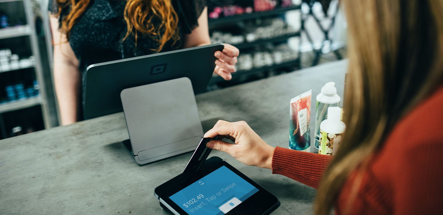 Hand swipes payment card at retail counter.