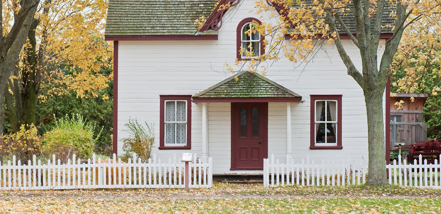 Front of a house with a yard and tree in front.