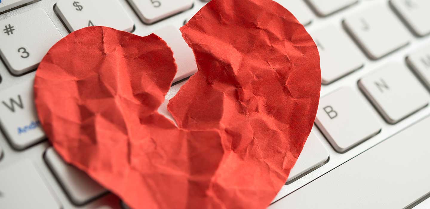 Ripped red foil heart on computer keyboard.