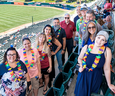 Employees wearing leis at a baseball game