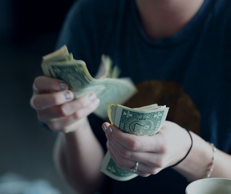 Close up photo of a woman counting dollar bills