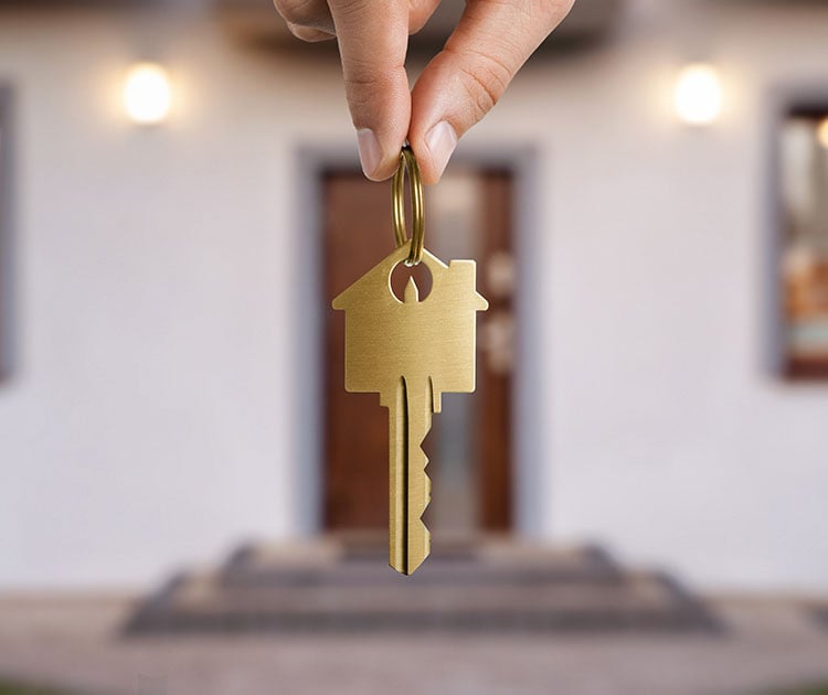 Close up of hand holding gold key to a dream house.